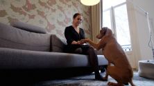 Standbild aus Patientenvideo: Protagonistin auf Couch, ihr Hund gibt Pfötchen