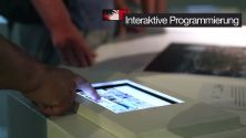 Standbild des Case-Videos: Finger eines Ausstellungs-Besuchers tippt auf Touchscreen