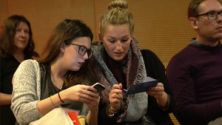 Standbild aus Kurzreportage: zwei junge Zuschauerinnen betrachten (gegenseitig) ihre Smartphones
