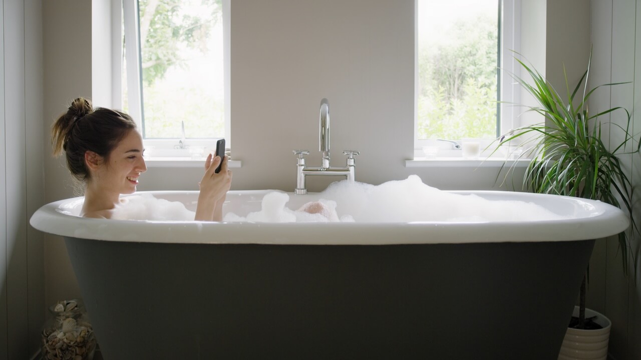 Standbild aus Imagefilm: Frau mit Smartphone in Badewanne